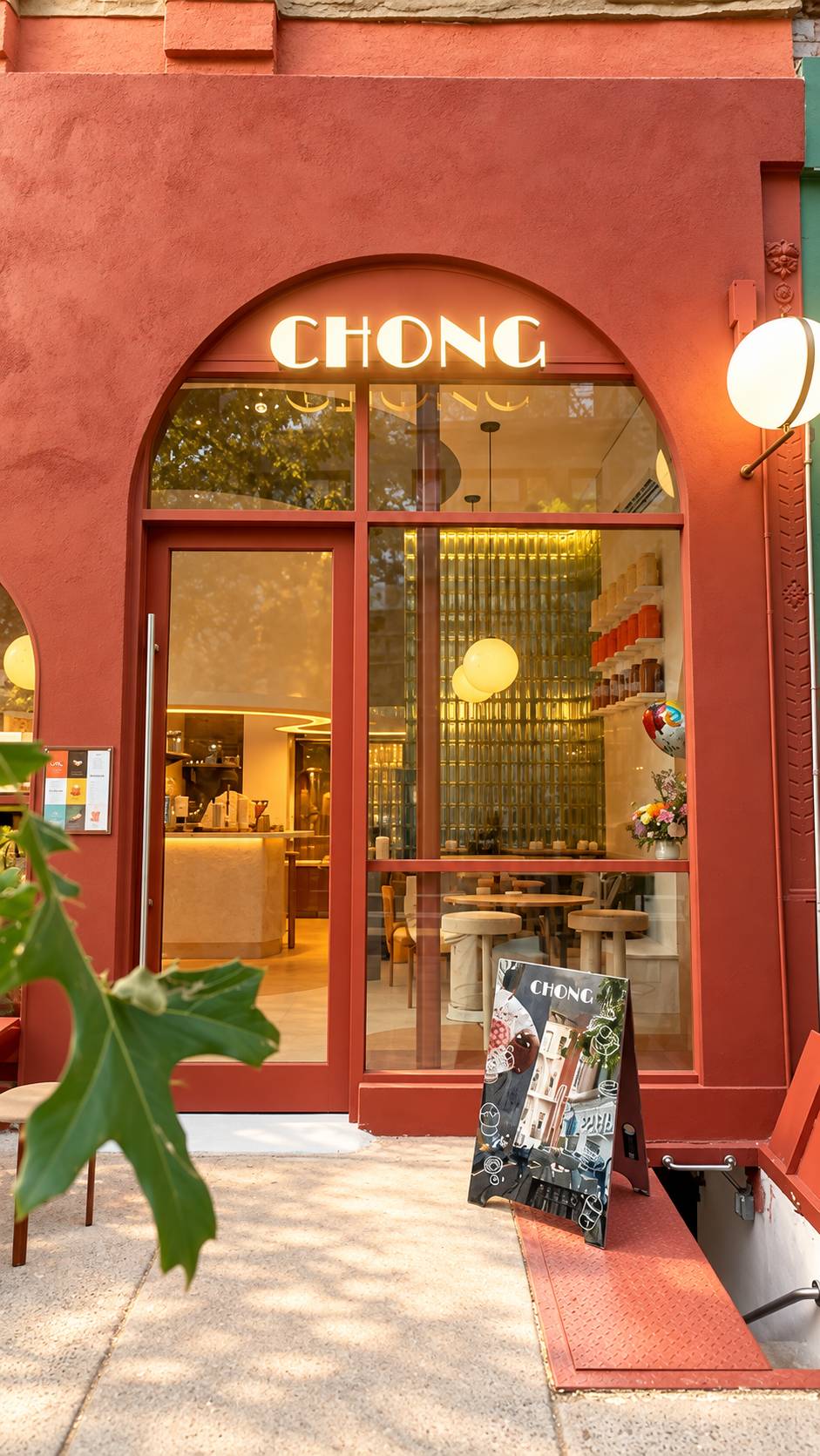 CHONG storefront: terracotta facade, arched window with the CHONG sign, round pendant lamp and a sidewalk sign.